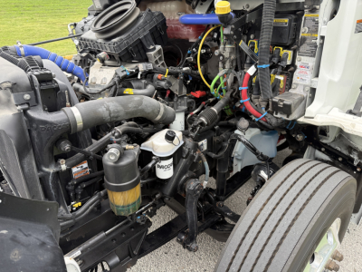 Kenworth T380 engine bay showing coolant reservoir, air intake, hoses, wiring, and various machine components.