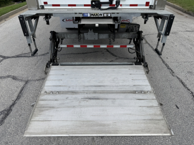 Truck rear showing hydraulic liftgate folded up, with platform extended slightly, undercarriage and bumper visible.