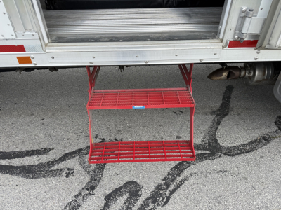 Kenworth T380 refrigerated truck with red fold-out steps under rear doors and cargo area visible.