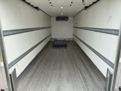 Interior of a refrigerated Kenworth truck cargo area showing empty box with aluminum E-track rails along walls, roof-mounted insulation panel, and a small pallet on the floor.