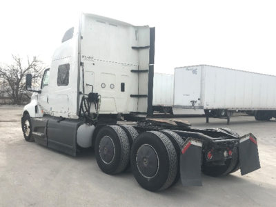 Truck tractor in-service showing side view with sleeper cab and tandem rear axles.