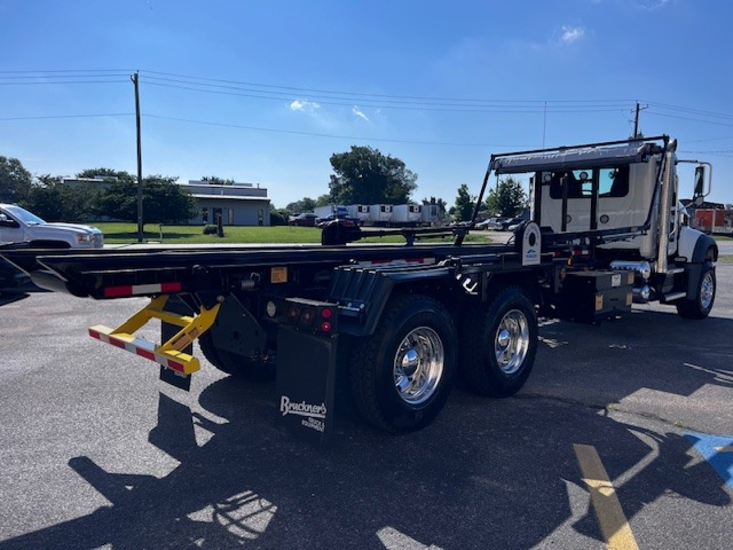 Mack GR64F truck roll-off chassis with extended frame, dual rear axles, and Crew cabin showing bare metal platform and hydraulic components.