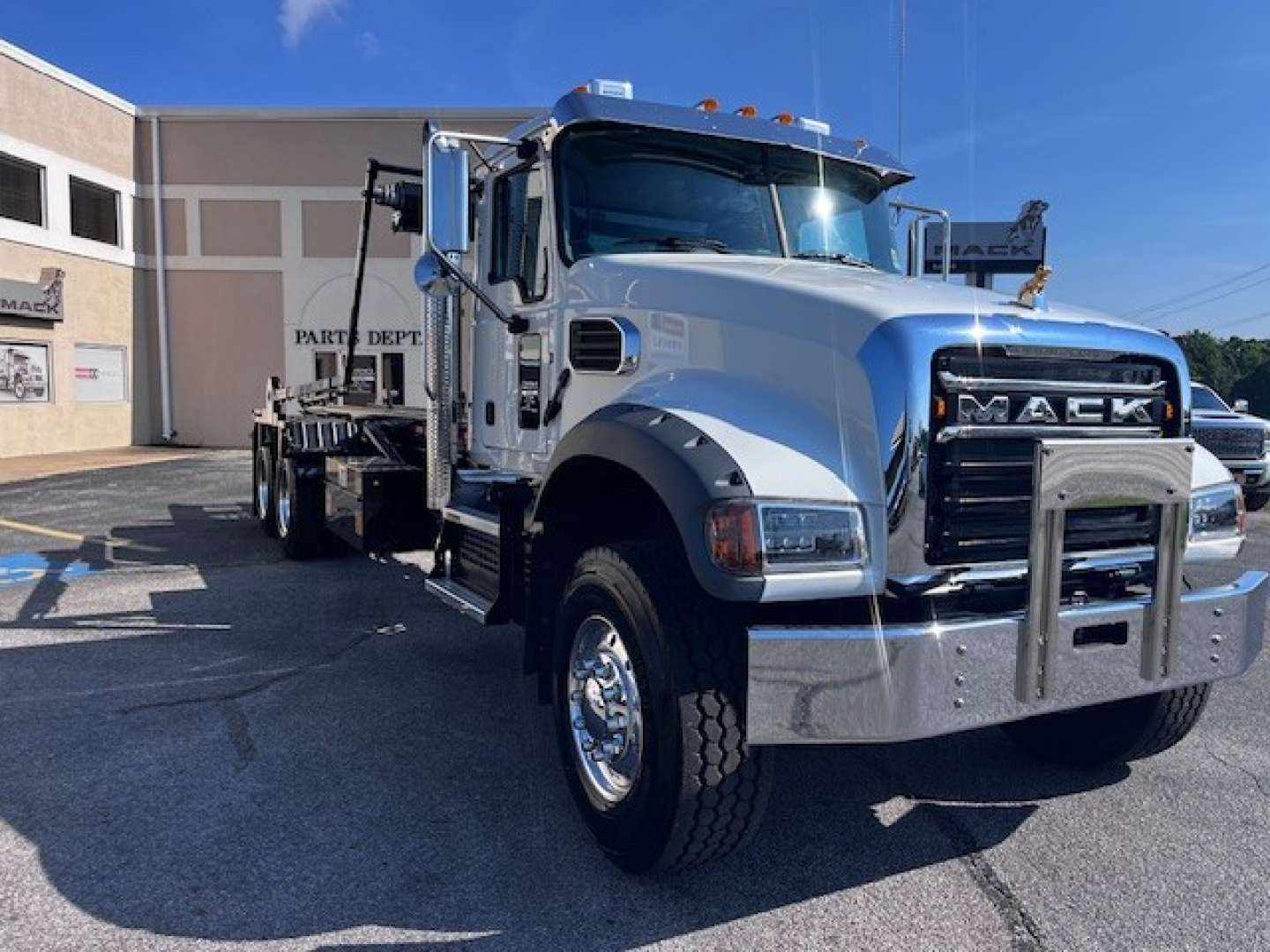 White Mack GR64F truck in a dealership lot with chrome bumper and grille, side view showing cab and bed.