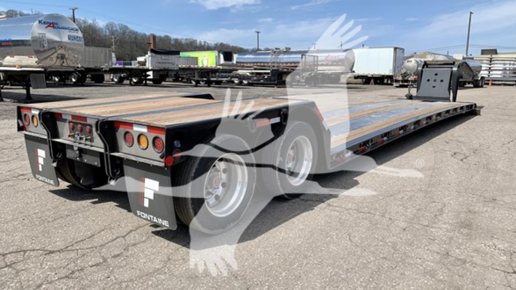 Lowboy trailer showing rear and loading platform, Fontaine logo on mudflaps, multiple lights, dual axles, and wooden deck. No visible text besides logos.