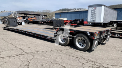 Fontaine N12 lowboy trailer showing dual rear axles and long flat deck with ramps in background; stock and VIN labels visible.