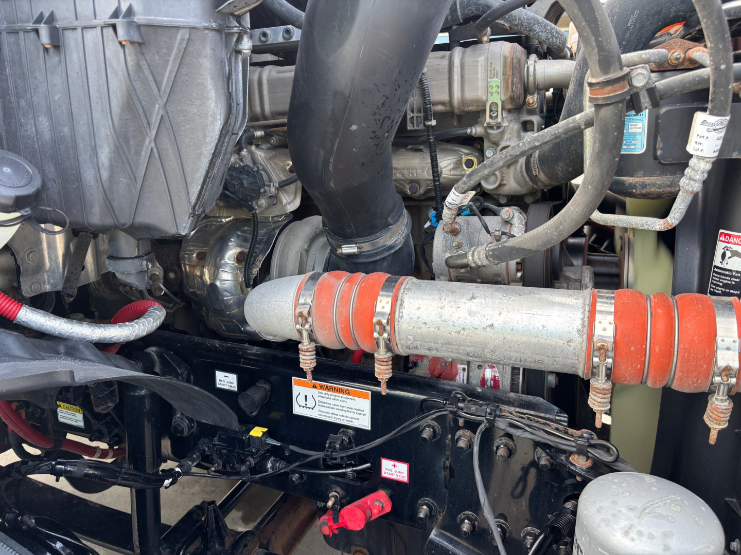 Truck engine bay showing radiator hose, coolant reservoir, hoses, and engine components in a Freightliner PE11664DC.