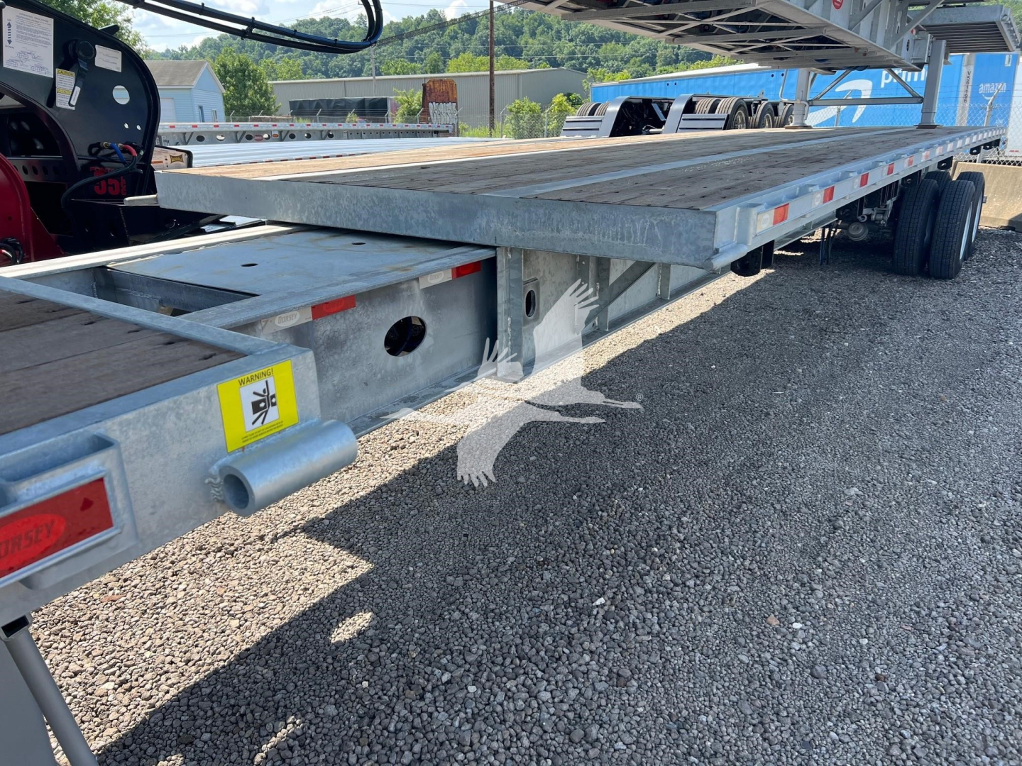 Flatbed trailer deck with Dorsey branding and VIN sticker; side rails, reflectors, and wheel axle visible undercarriage; tag shows 2027 Dorsey Extendable trailer.