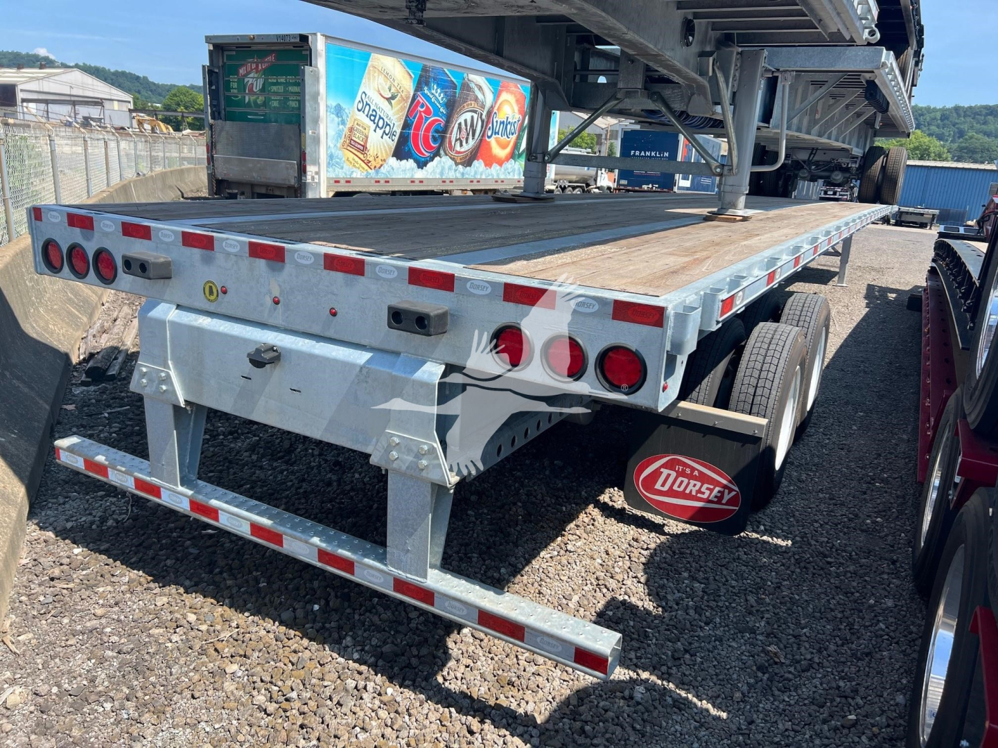 Flatbed trailer rear/side view showing Dorsey-branded mudflap and rear lights, metal deck, dual rear axles, and warning reflectors.