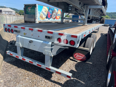 Flatbed trailer rear/side view showing Dorsey-branded mudflap and rear lights, metal deck, dual rear axles, and warning reflectors.