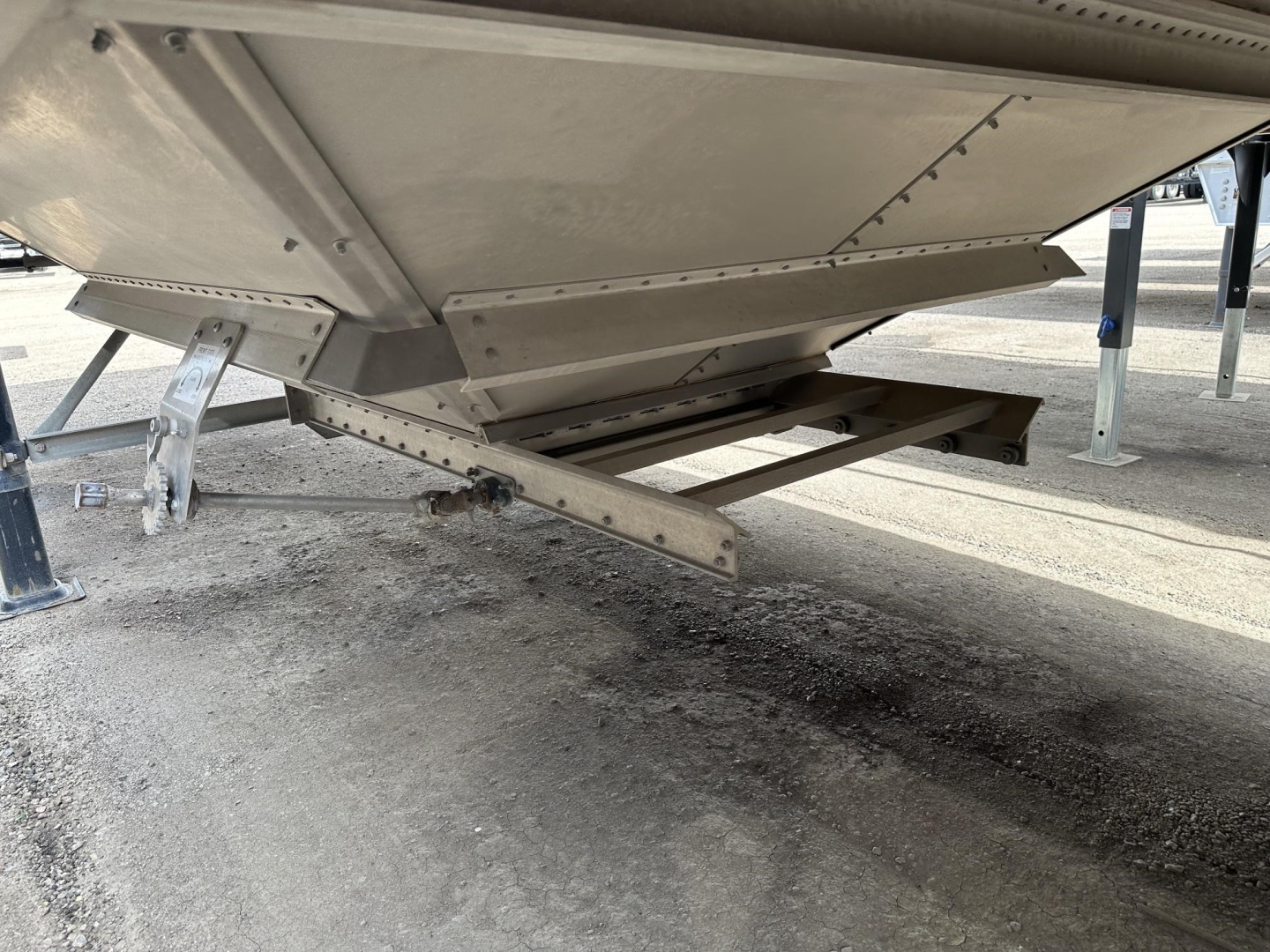 Grain trailer underside showing air ride suspension and hopper frame with metal support beams and landing legs.