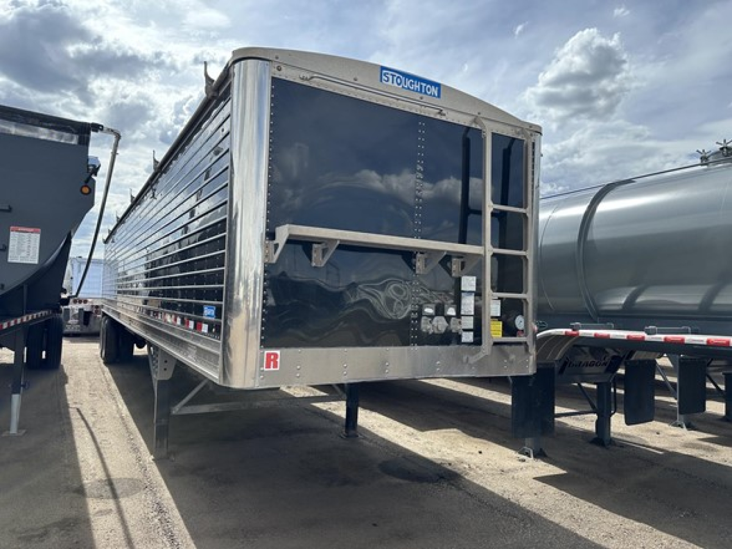 Stoughton air ride grain trailer in-service showing front end with label SToughton and rear access ladder. VIN 150120529475, stock 82467, hopper-type trailer with aluminum sides, rear underride area.