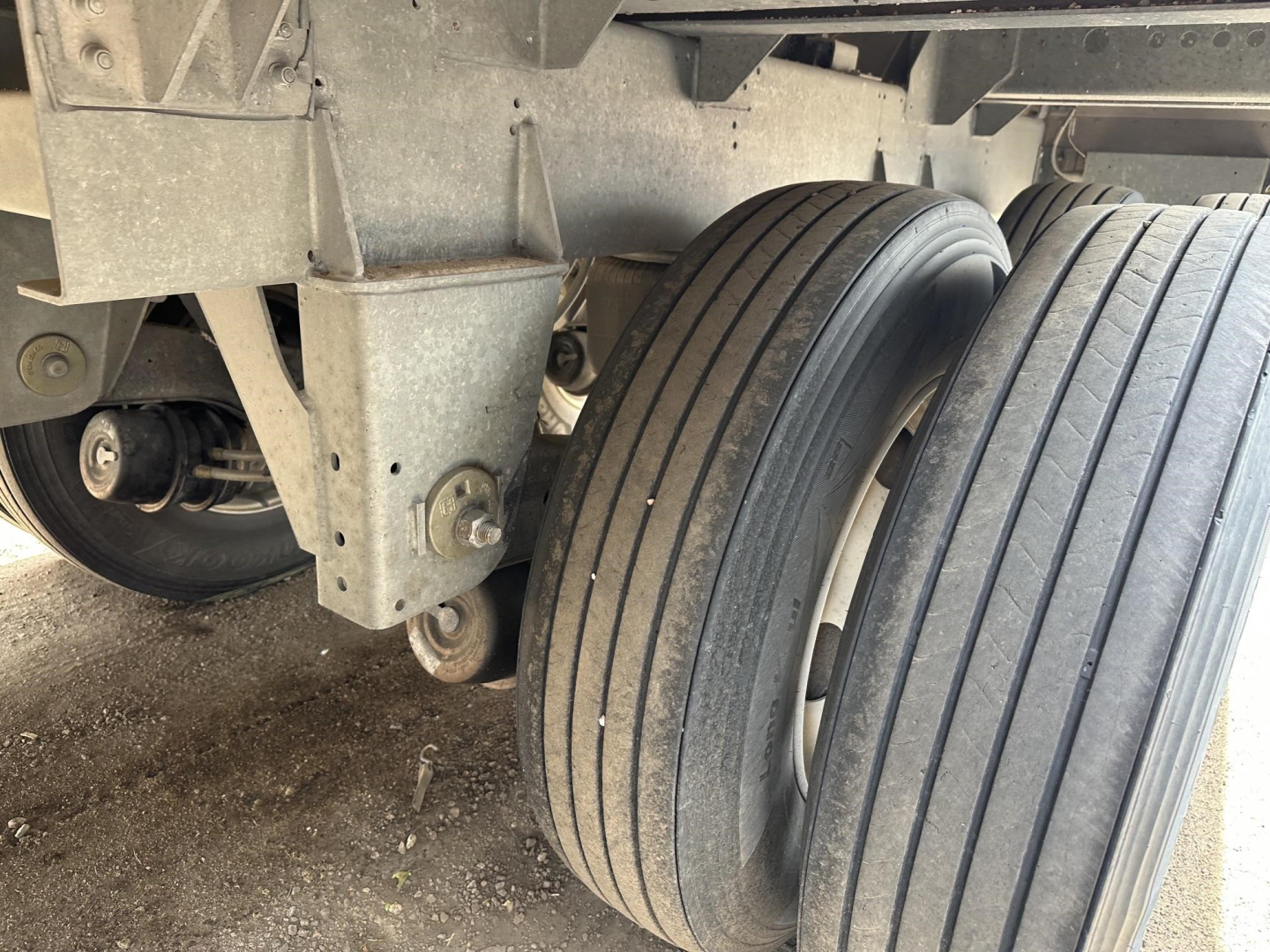 Front left view of 2025 Stoughton Air Ride Grain Trailer showing dual tires and suspension components.