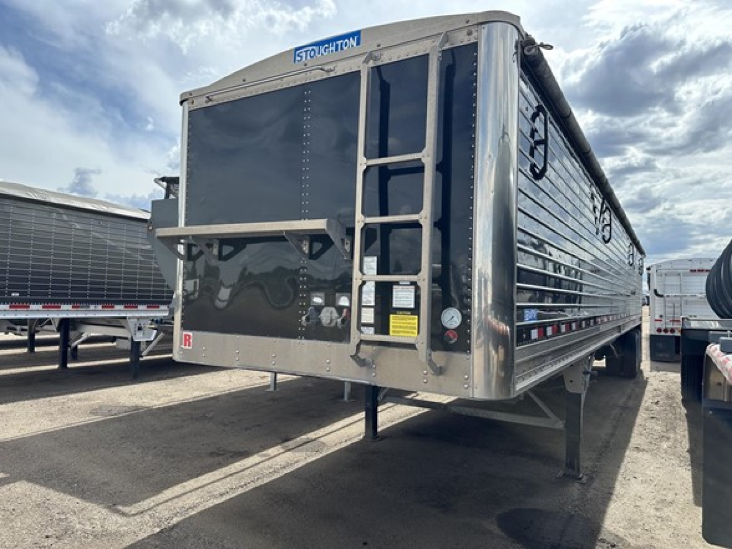 Stoughton air ride grain trailer hopper showing rear entry ladder and frame with Stoughton branding and reflective markings.