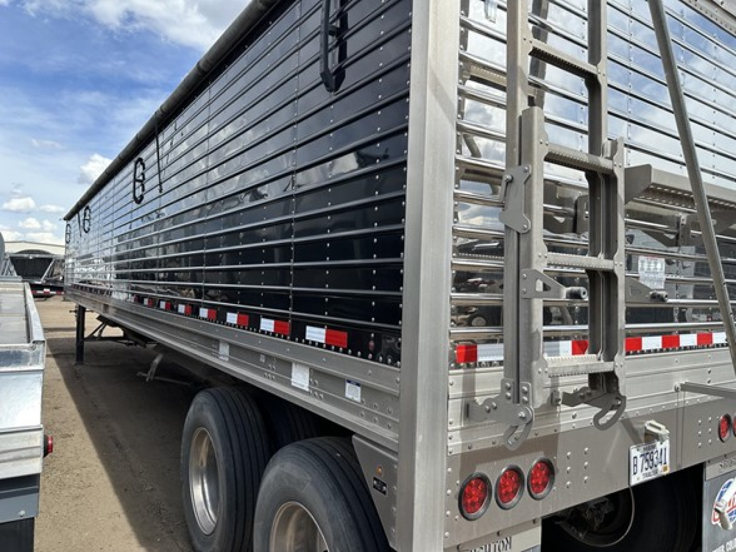 Stoughton air ride grain trailer side view showing polished aluminum exterior, rear access, dual rear wheels, lights, and reflective tape.