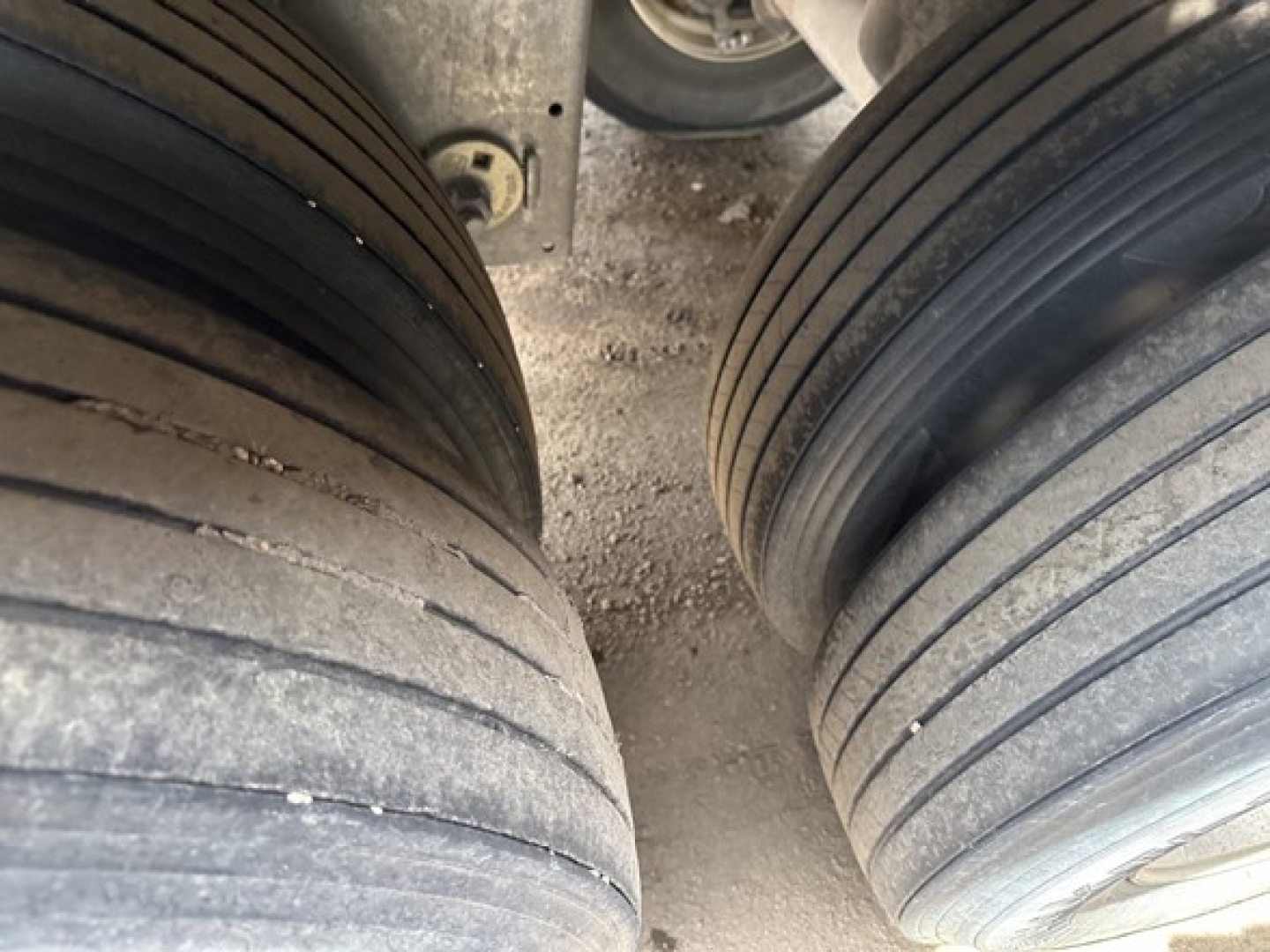 Stoughton air ride grain trailer wheel drums showing dual tires and a dusty road surface between the axles.