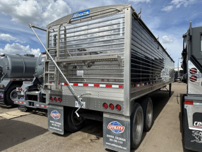 Stoughton air ride grain trailer in rear three-quarter view showing aluminum side panels, top rail, rear gates, dual rear axles, and mud flaps with Utility Truck equipment logo.