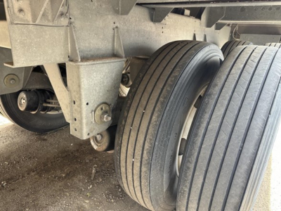 Trailer wheel assembly and suspension undercarriage showing dual rear tires and landing gear mounting points.