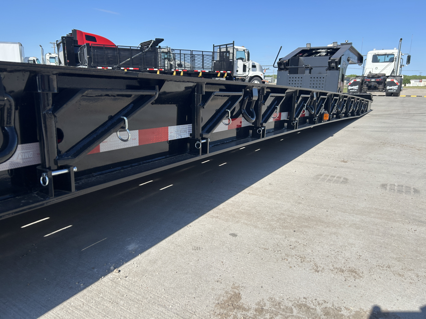 Lowboy trailer showing side deck with structural frames and bolster hooks.