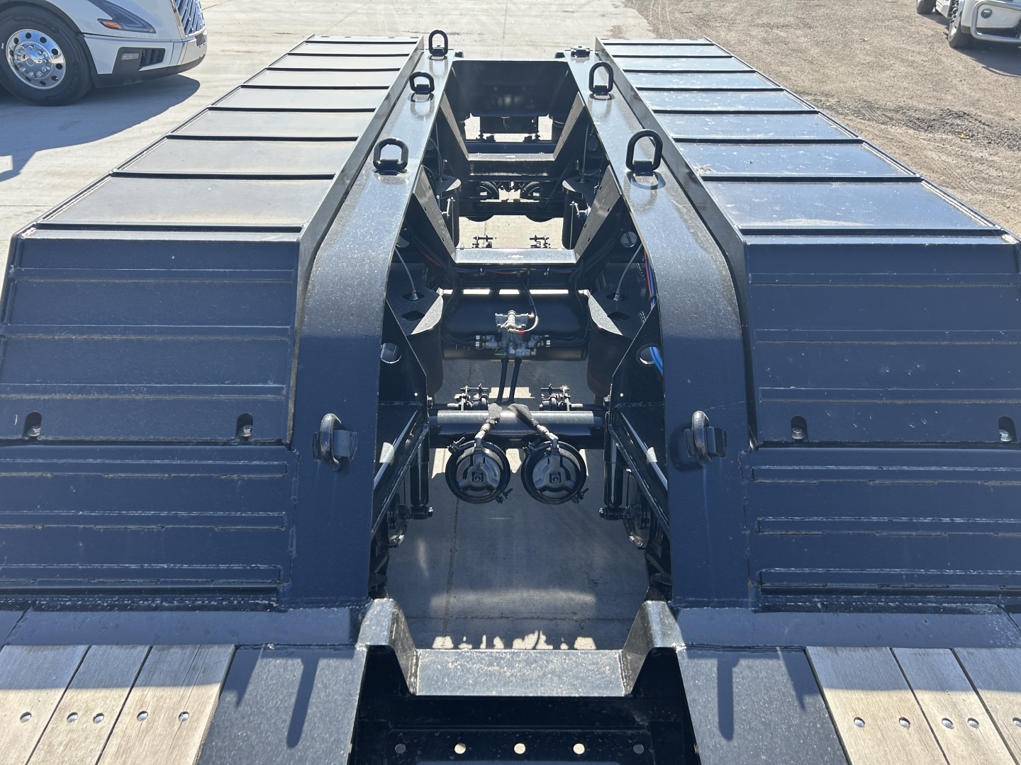 Trailer chassis and hitch area of a Load King 503/554 SS SF lowboy trailer showing central kingpin platform and side tool boxes.