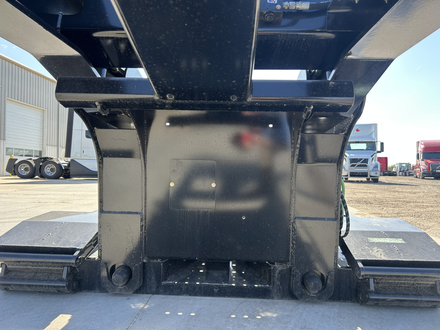 Loader hitch/kingpin area of a Load King trailer viewed from the front, showing a black steel frame and support components.