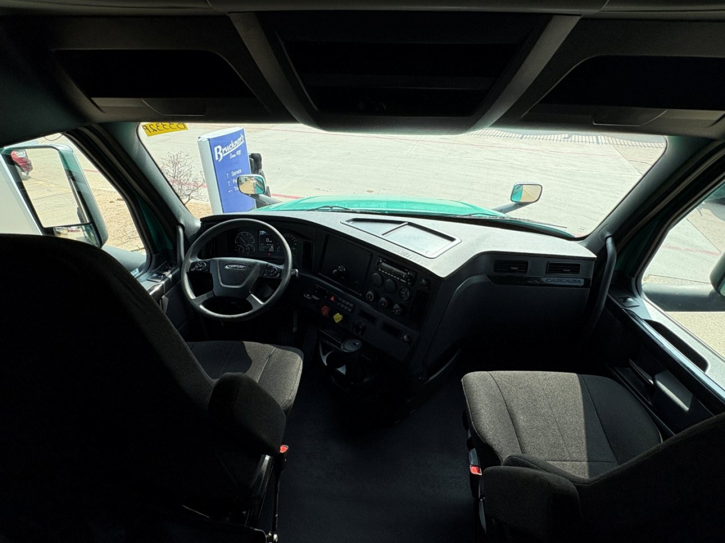 Cab interior of a 2023 Freightliner Cascadia 126 truck showing steering wheel, dashboard with gauges, and driver and passenger seats.