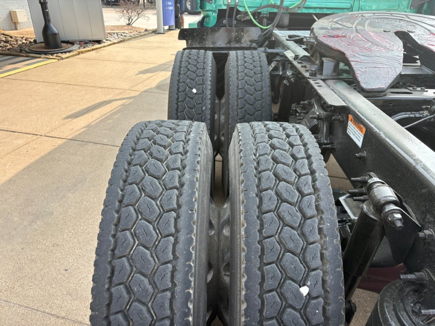 Truck rear dual tires and chassis of a Freightliner Cascadia 126 tractor showing dual rear axles and tire tread detail.