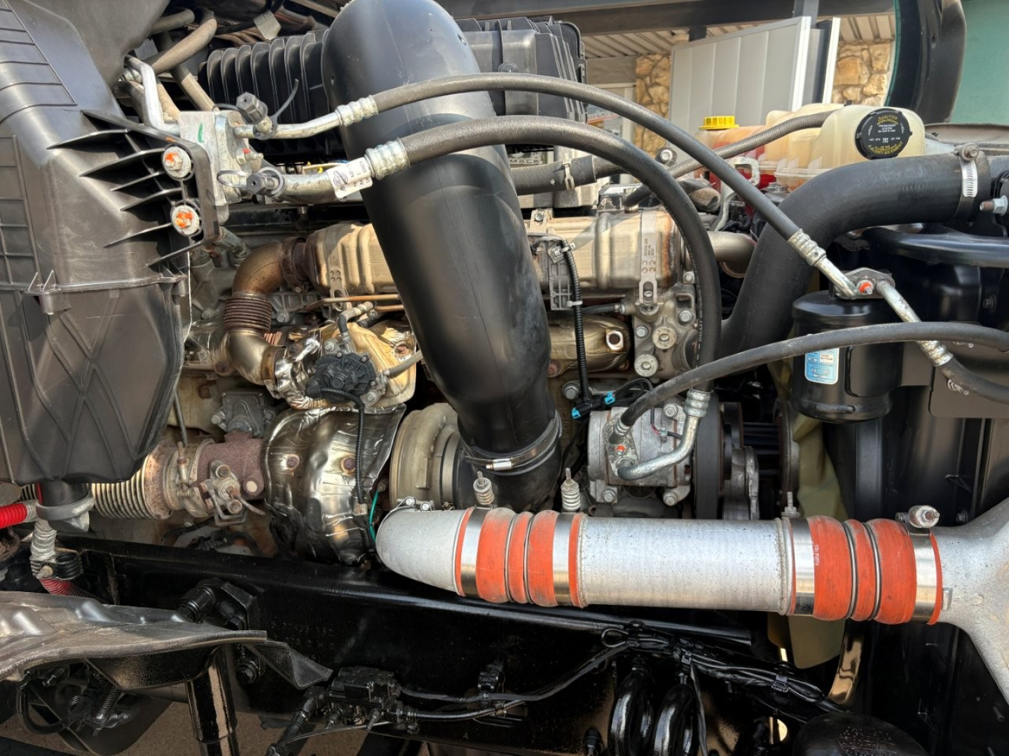 Diesel engine bay of a Freightliner Cascadia 126 cabover showing intake manifold, hoses, and turbo components.