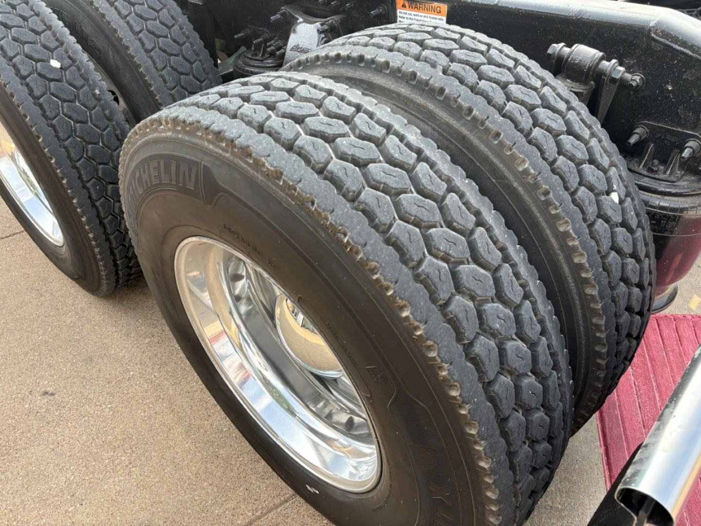 Truck rear dual tires of a Freightliner Cascadia 126 tractor showing tread and chrome wheels.