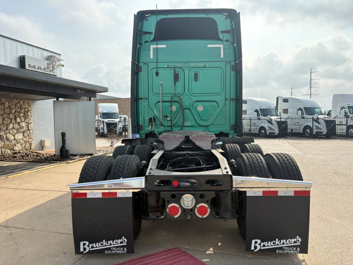 Truck rear view of a 2023 Freightliner Cascadia 126 sleeper tractor showing rear chassis and dual rear axles with mud flaps and taillights.