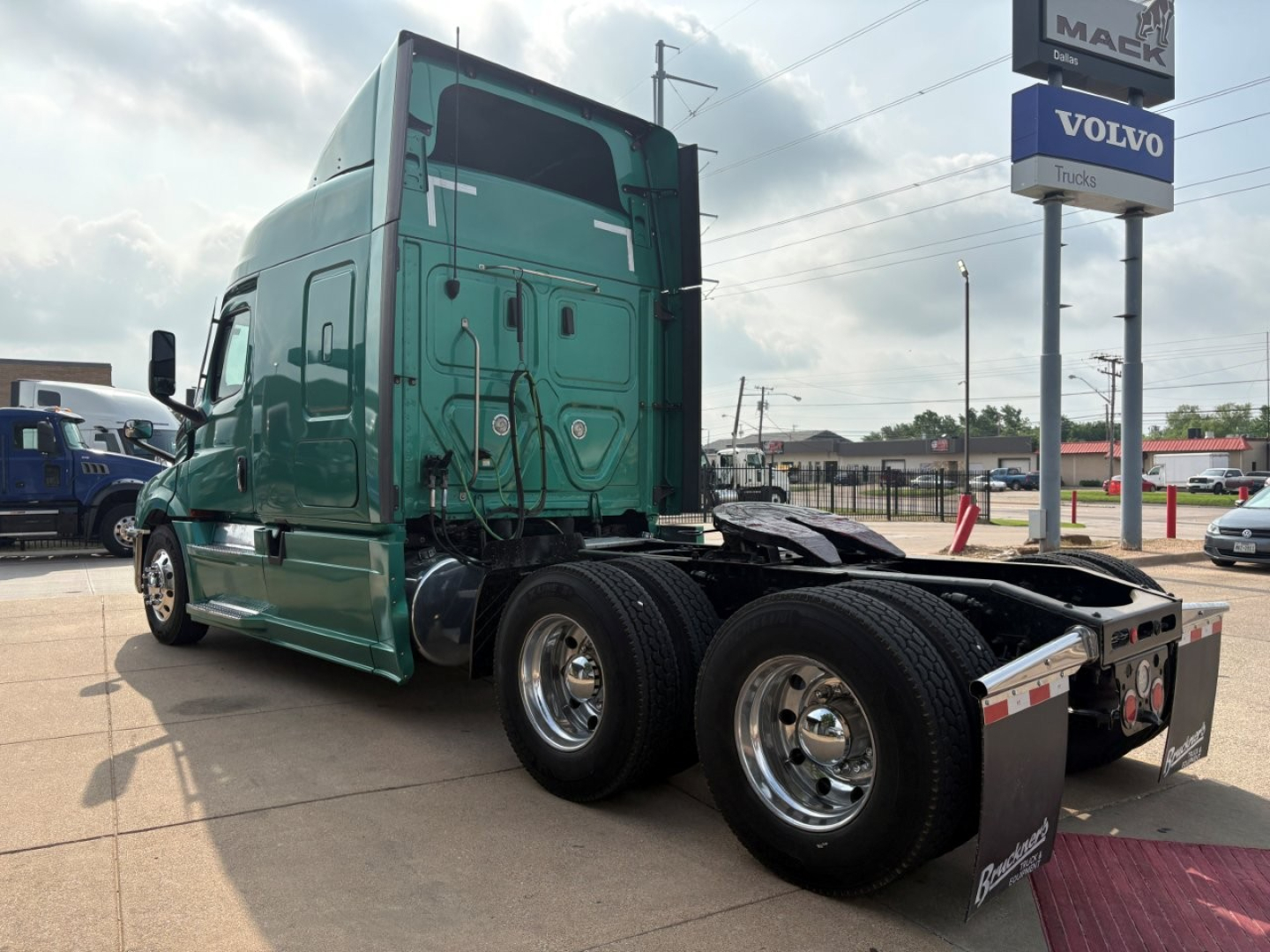 Truck cab and rear section of a green 2023 Freightliner Cascadia 126 tractor with dual rear axles and fifth-wheel area visible.
