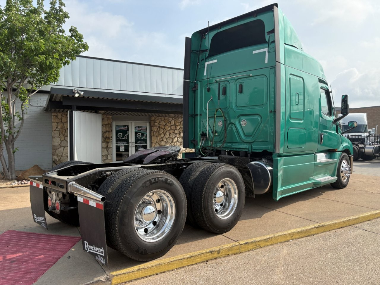 Freightliner Cascadia 126 tractor rear view showing tandem axles and green cab.