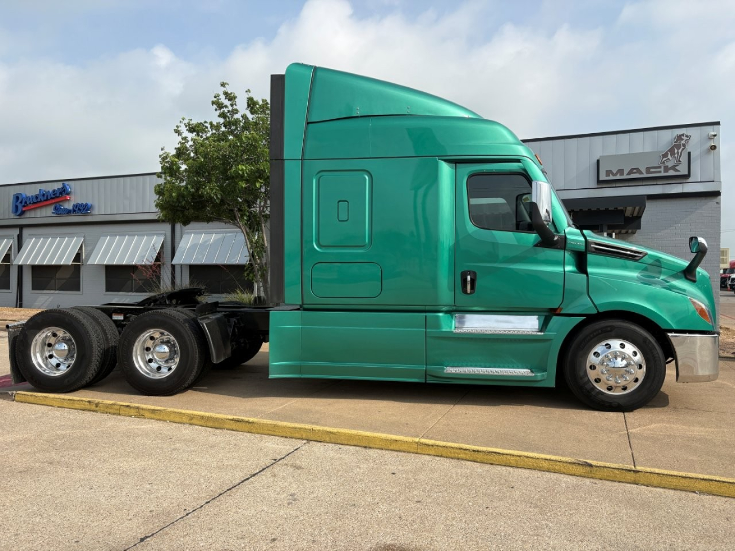 Truck side view of a green 2023 Freightliner Cascadia 126 sleeper cab with dual rear axles and chrome wheels.