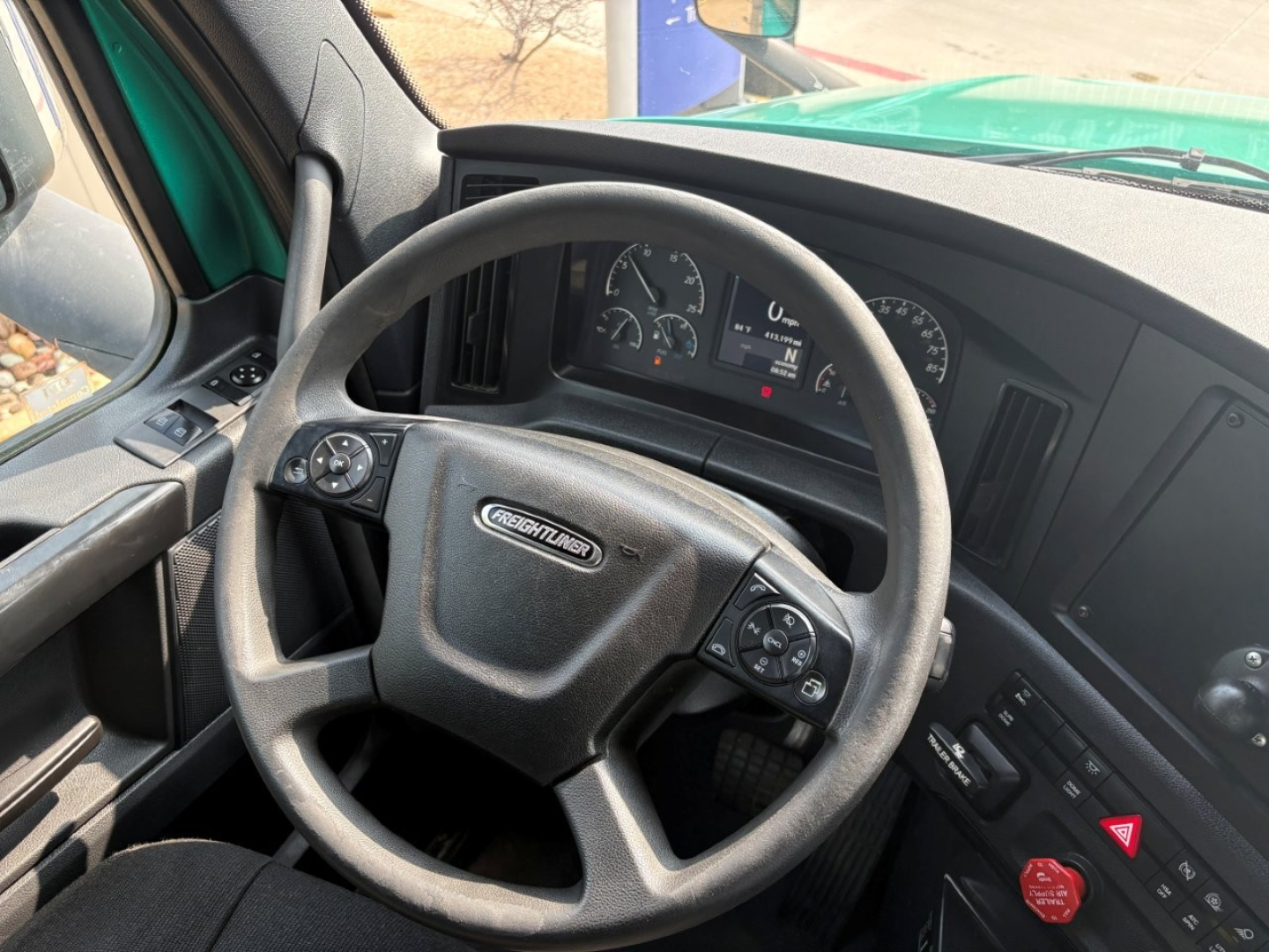Freightliner Cascadia truck interior steering wheel with dashboard gauges and controls visible.