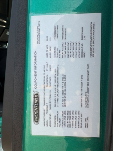 Freightliner information placard on green truck showing component information, VIN, weight ratings, and manufacturer details.