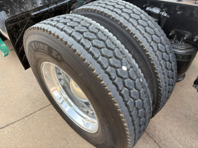 Dual rear tires of a Freightliner Cascadia 126 truck showing dual 22.5 inch tires with Kline branding on the tire sidewall and polished wheel rims.