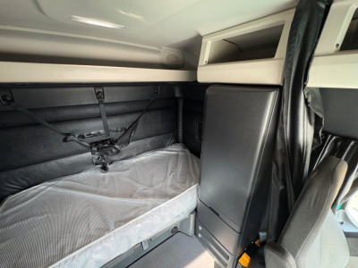 Freightliner Cascadia 126 truck sleeper cab interior showing bunk bed area with mattress, side storage cabinet, and overhead shelf.