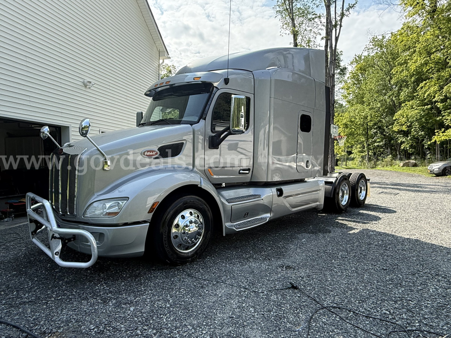 2019 Peterbilt 579 truck with a chrome grille and silver cab, long-haul tractor, dual rear axles, fuel tanks along side, day-time outdoor lot.