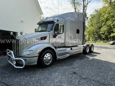 2019 Peterbilt 579 truck with a chrome grille and silver cab, long-haul tractor, dual rear axles, fuel tanks along side, day-time outdoor lot.