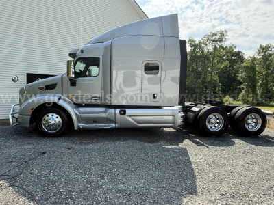 Peterbilt 579 cab with sleeper showing side profile and rear wheels, tag mentions 2019 model, chrome wheels, silver paint, no trailer attached.