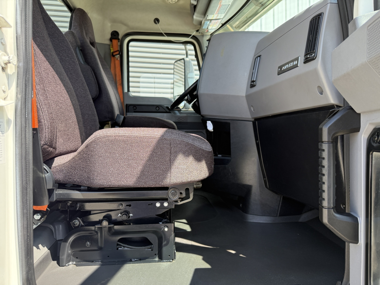 Mack AN64T cab interior showing driver and passenger seats, dashboard, and steering column. Text visible includes 'MACK' on the dash and control panel areas.