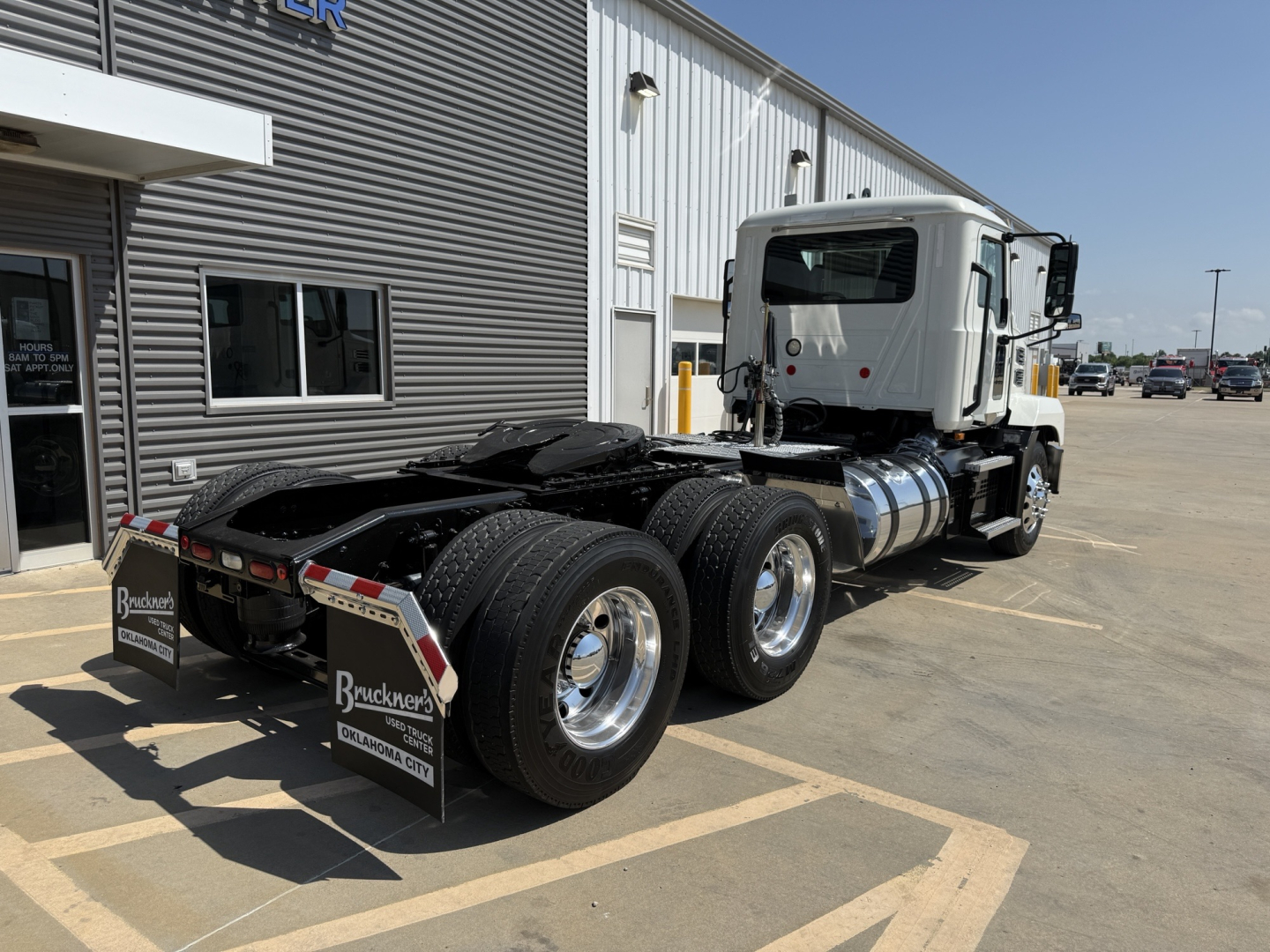 Mack AN64T conventional daycab tractor in service showing dual rear axles and chassis with fuel tanks and fifth wheel in a dealership lot.