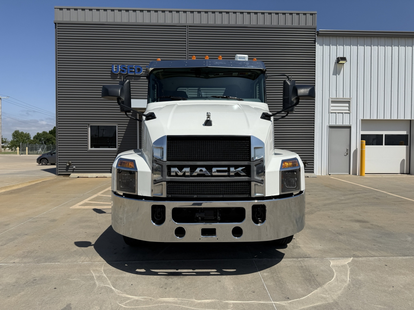 Front view of a white 2021 Mack AN64T truck in a dealership lot with grille, bumper, and headlights visible.