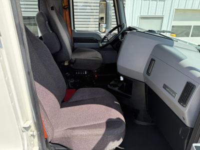 Truck cab interior of a 2021 Mack AN64T showing driver seat, passenger seat, steering wheel, dashboard, and center console with minimal visible controls.