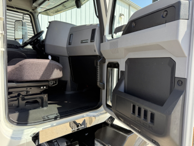 Cab interior of a 2021 Mack AN64T truck showing driver seat, dashboard, and open door with storage panels visible.