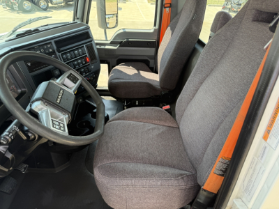 Mack AN64T truck cab interior showing steering wheel with integrated controls, dashboard, and two front seats in gray fabric.