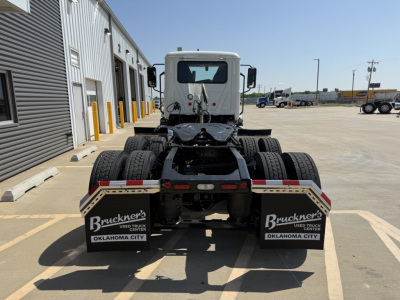 Rear view of a white Mack AN64T daycab tractor showing dual rear axles with mud flaps labeled Bruckner's Oklahoma City and stock area.