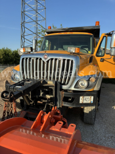 International 7400 plow truck front view showing chrome grille, amber cab lights, and plow attachment.
