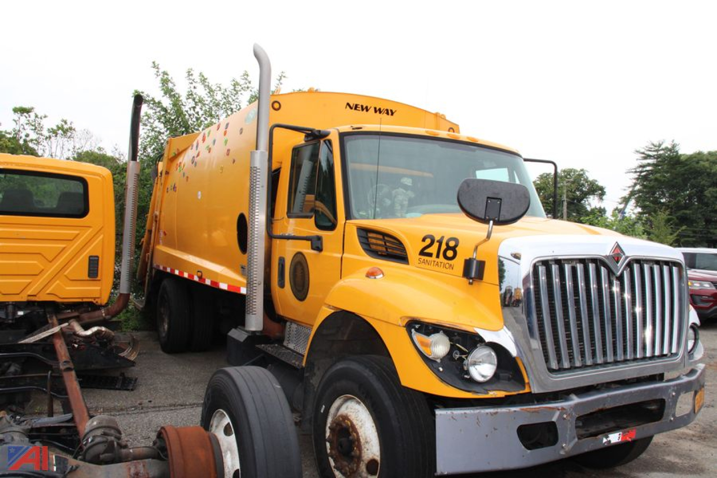 Truck cab of a yellow 2013 International WorkStar 7300 Packer with front grille and windshield, showing '218' on door and New Way unit on top.