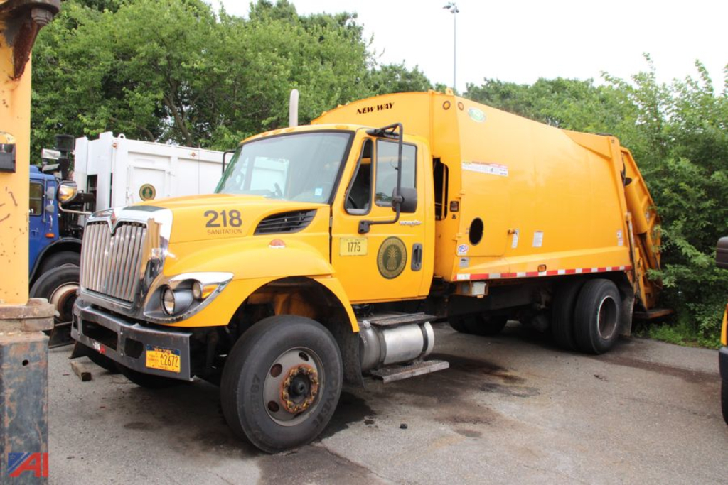 2013 International WorkStar 7300 Packer truck in yellow with a large rear hopper and front bumper; side view showing number 218 on door