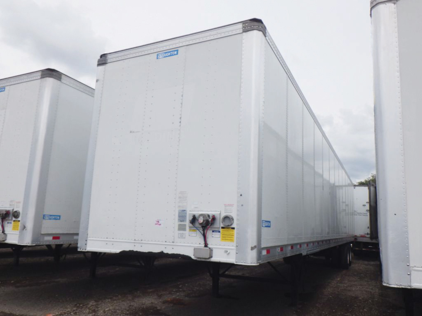 Trailer box showing Stoughton plate van with white exterior, front nose, and undercarriage with landing gear and hitch visible.